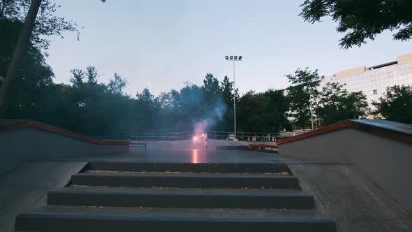 Aggressive Inline Roller Skater Doing Tricks in Concrete Skatepark with Red Burning Signal Flare