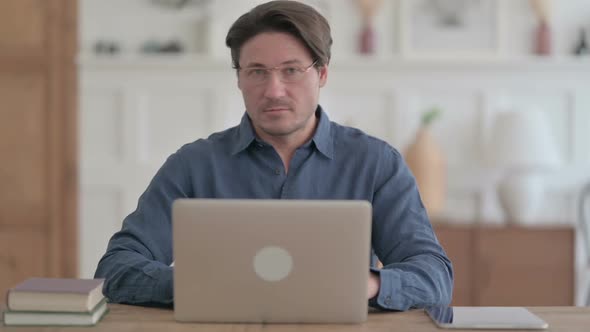 Young Man Shaking Head as No Sign while using Laptop in Office