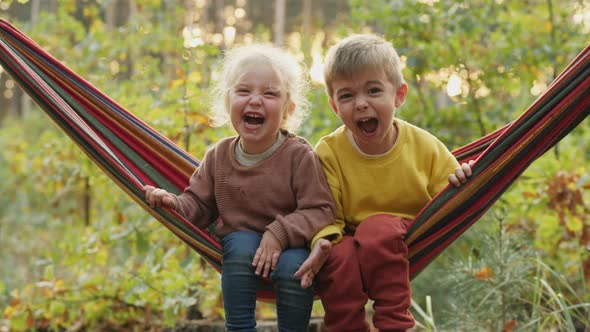 Two Children Screaming Loudly While Sitting in a Hammock