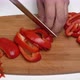 Cook Chopping Red Bell Pepper with Sharp Knife into Small Slices on Wooden Kitchen Cutting Board - VideoHive Item for Sale