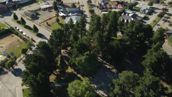 Aerial rising over a pine tree octagonal square in the middle of Trevelin town, Patagonia Argentina