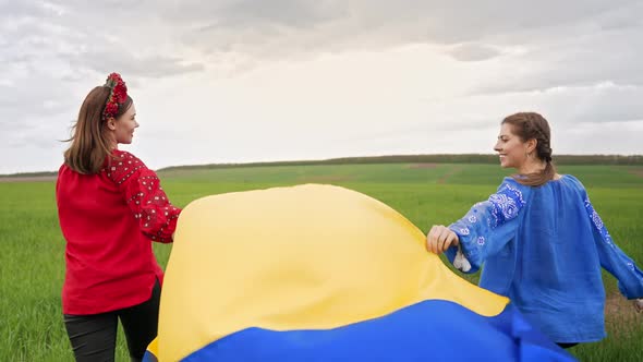 Happy Ukrainian Women with National Flag Walking in Green Field