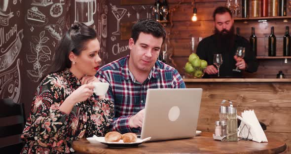 Couple Drinking Coffee and Looking at Computer Screen