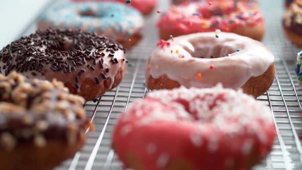 Sprinkling candy chocolate on frosted doughnut. Slow Motion. alt
