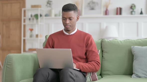 African Man Shaking Head as Yes Sign while using Laptop in Office