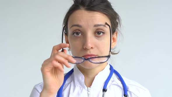 Female Doctor is Putting Off Protective Blue Gloves Isolated on White Background After Some Medical