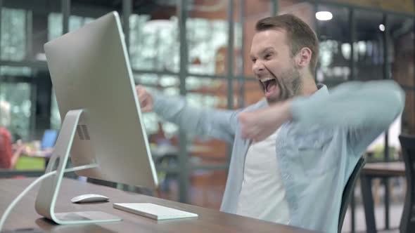 Excited Young Man Celebrating Success at Work