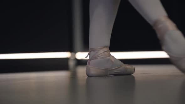 Elegant Ballerina Moving Feet Together and Standing Up on Tiptoes. Close-up of Ballet Dancer's Feet