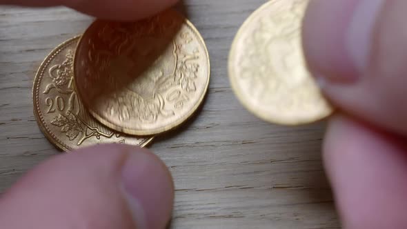 Male hand stacked golden shiny swiss coins on wooden table,close up