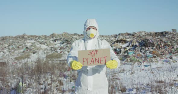 Man Wore in Protective Suit Shows Protest Sign "Save the Planet" at Camera