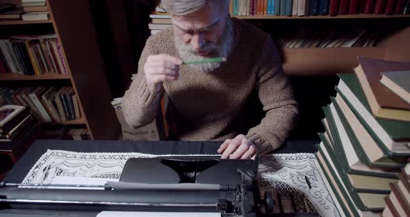 Footage of an old writer working from the library, using vintage typewriter, 4k