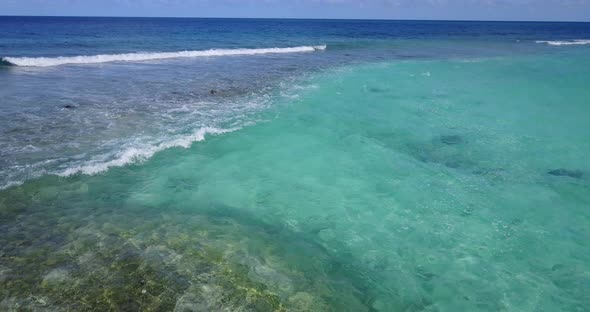 Daytime flying copy space shot of a sandy white paradise beach and aqua blue ocean background in hig