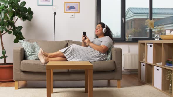 Woman in Headphones Listens To Music on Smartphone