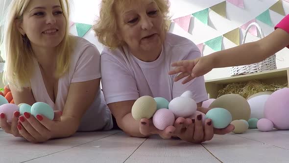 Pretty Little Girl Giving Decorated Eggs and Greeting Cards to Mother and Grandmother at Easter