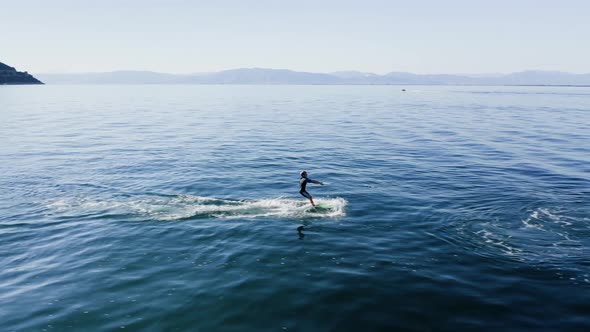 Drone view of kid doing water ski in the sea.