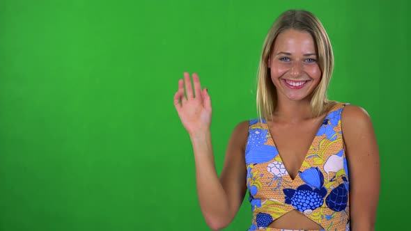 Young Pretty Blond Woman Waves with Hand - Green Screen - Studio