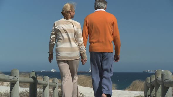 LS OF A SENIOR COUPLE WALKING TO THE BEACH