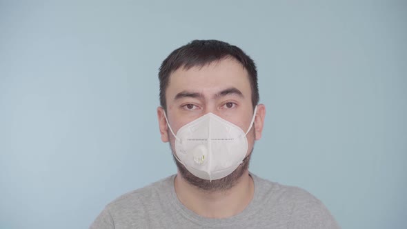 Portrait of a bearded man in a protective mask n95 on a blue background