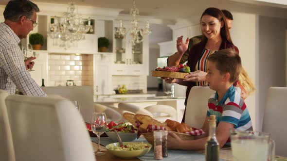 Happy caucasian parents, children and grandfather preparing table for family meal