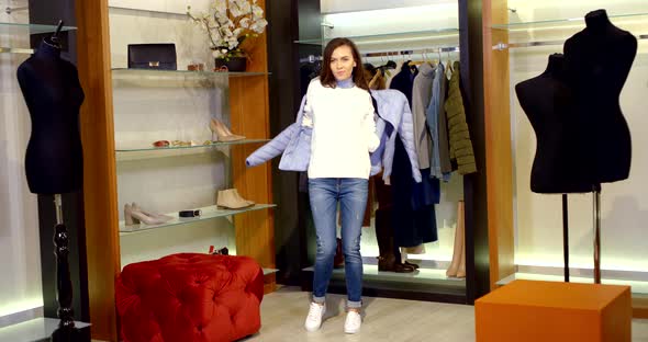 A Dark-haired Young Woman Is in a Large Women's Wardrobe Fitting Room with Mannequins and Different