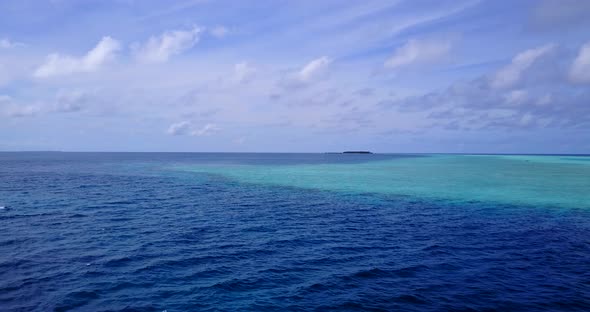 Luxury fly over travel shot of a sandy white paradise beach and aqua blue ocean background in high r