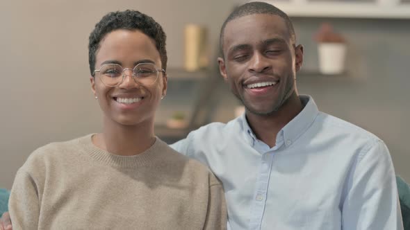 Portrait of Couple Smiling at Camera While Sitting on Sofa