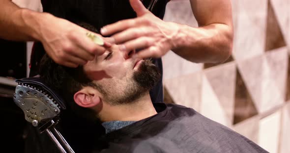Mid section of hairdresser applying cream on clients beard