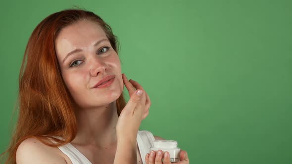 Attractive Young Red Haired Woman Applying Face Cream