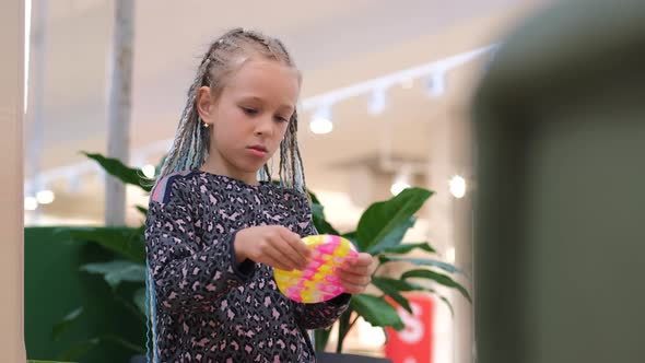 Girl Playing with Antistress Hand Toy in Mall