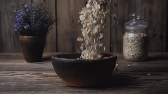 Slow motion of oatmeal falling into a bowl on a wooden table