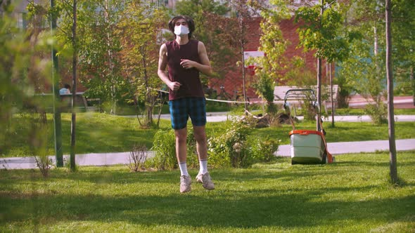 A Young Man in Medical Mask Warming Up in the Park Then Continue Running