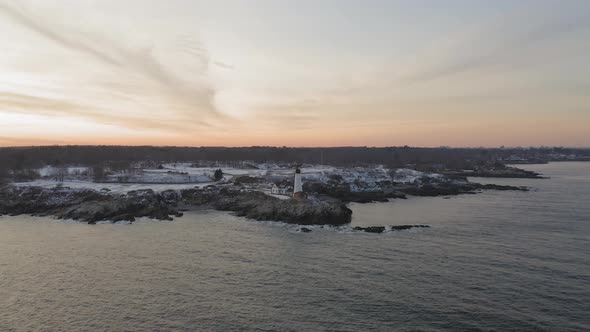 Slow AERIAL SLIDE past Portland Head Light, winter sunset