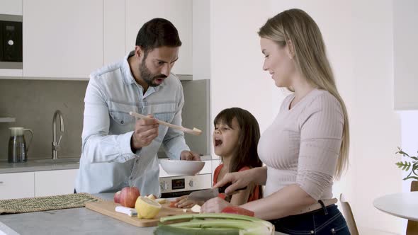 Happy Young Parents Couple and Little Girl Cooking Dinner