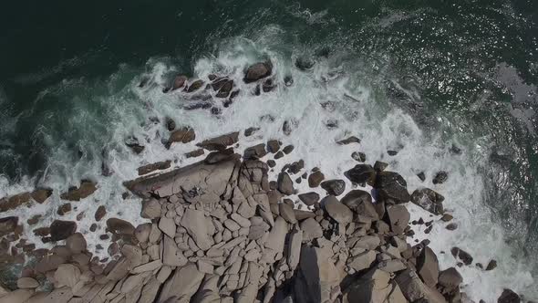 View From a Drone Vertically Down on a Stone Cape Washed By Strong Waves