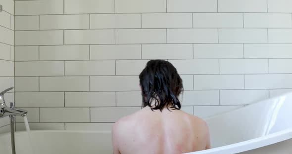 Woman with Bare Back and Wet Hair Shakes Sitting in Bath