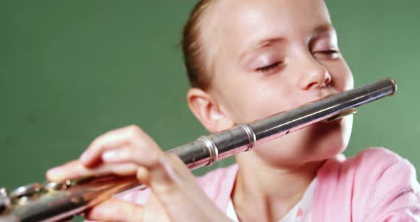 Schoolgirl playing flute in classroom at school