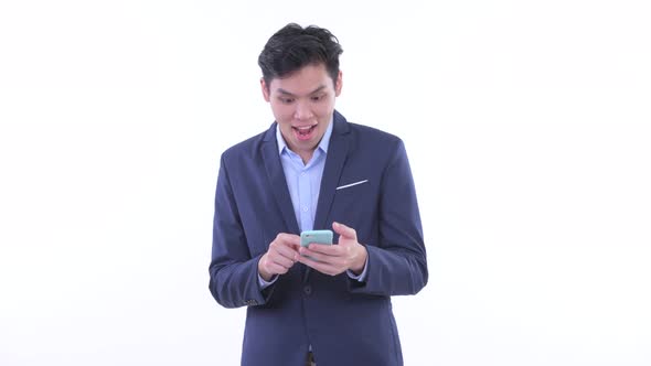 Happy Young Asian Businessman Using Phone and Getting Good News