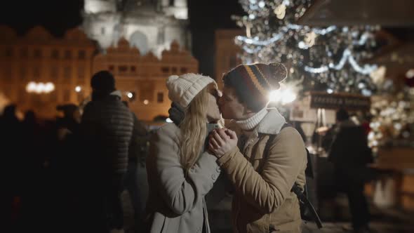 Cute Portrait of Couple Kissing During Holiday Season Celebrating Outside in European Town