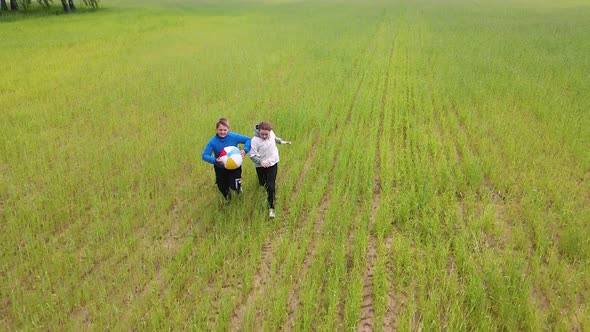 Happy Boy and Girl Running with a Ball in the Field Slow Motion