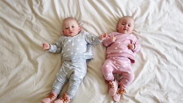 Two girls sisters lie on the bed. Two baby twins on the bed