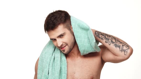 Positive Caucasian Topless Male with Tattoed Hand Wiping Head with a Towel Around His Neck Standing