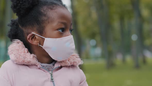 Close Up Kid Face Little Girl in Medical Mask Looks Away Turning Head Looking at Camera in City