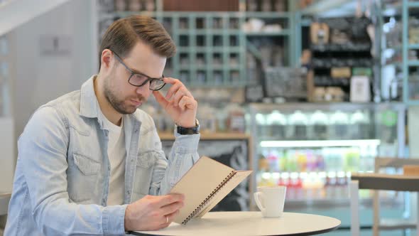 Man Reading Book in Cafe