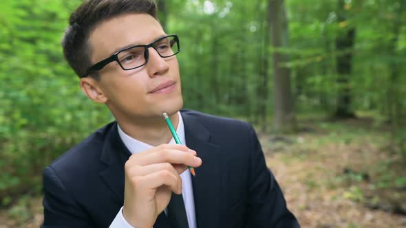 Young Businessman Writing Good Ideas, Working at Office Desk in Green Forest