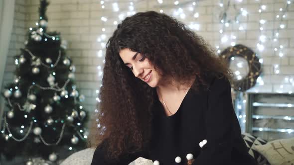 Girl packing gift. Young beautiful woman wraps Christmas gifts while sitting on bed