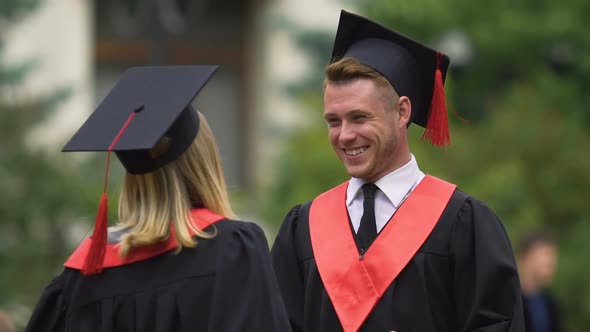 Young People in Academic Gowns Embracing Cheerfully, Exchanging Congratulations