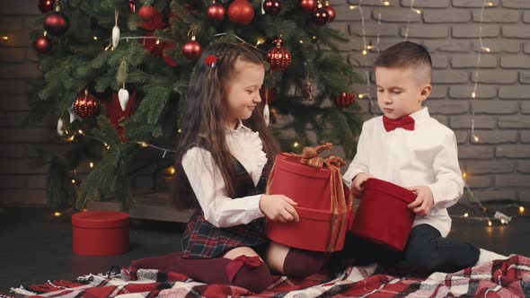 The Little Kids Holding Gifts Near the Christmas Tree