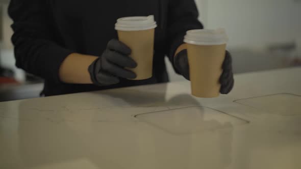 Unrecognizable Bartender in Black Gloves Passing Two Coffee Cups To Caucasian Man Over Counter