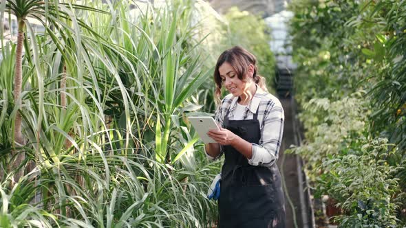 Woman in Uniform Checking Plants at Indoor Plantation