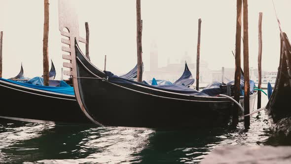 Close-up Shot of Beautiful Traditional Empty Gondolas with Rain Covers Rocking on Waves at Foggy